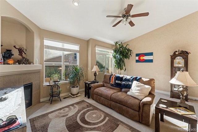 living room with light carpet, vaulted ceiling, ceiling fan, and a tile fireplace