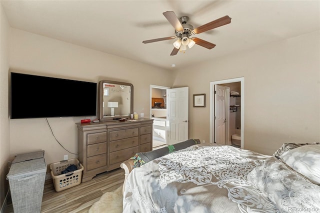 bedroom featuring ceiling fan, light wood-type flooring, connected bathroom, and a spacious closet