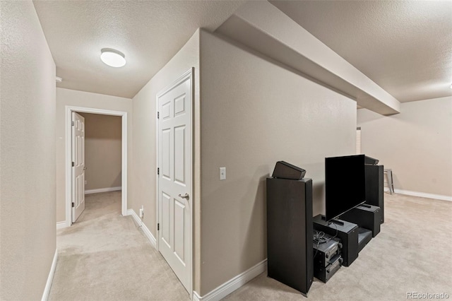 corridor featuring light carpet and a textured ceiling