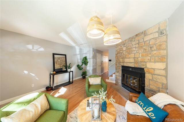 living room featuring a stone fireplace and wood-type flooring