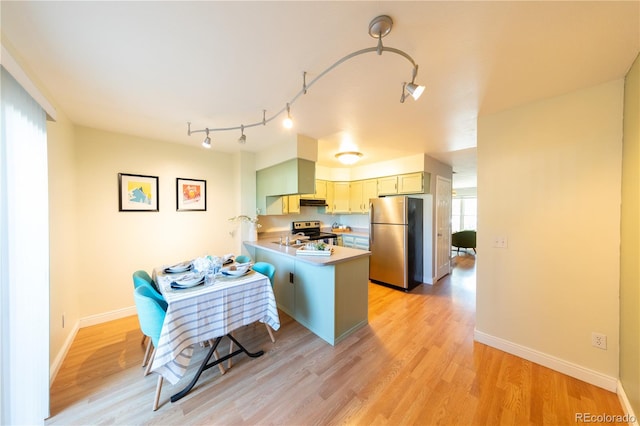 kitchen featuring appliances with stainless steel finishes, kitchen peninsula, and light hardwood / wood-style flooring