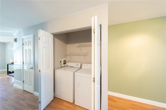 clothes washing area with light hardwood / wood-style floors and washer and dryer