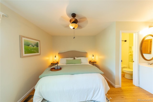 bedroom featuring ceiling fan, light hardwood / wood-style floors, and ensuite bath