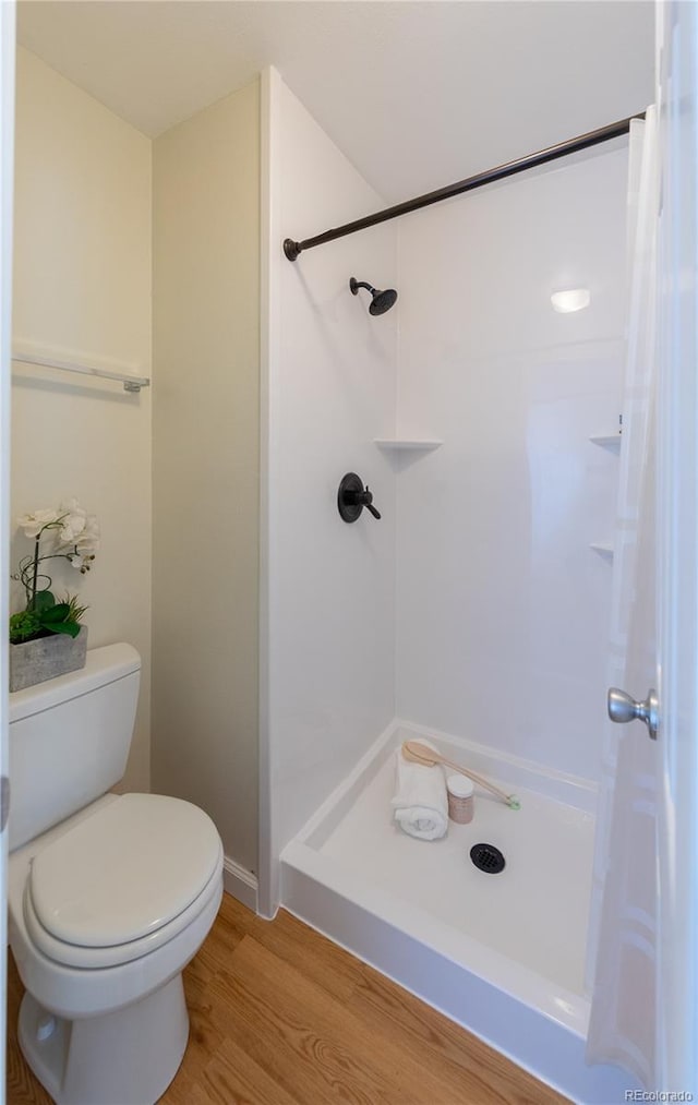 bathroom with toilet, hardwood / wood-style flooring, and a shower with shower curtain