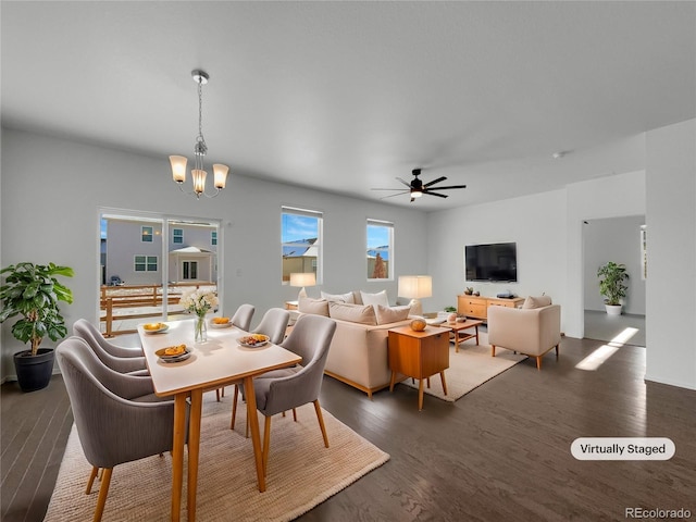 dining area with ceiling fan with notable chandelier and dark hardwood / wood-style floors