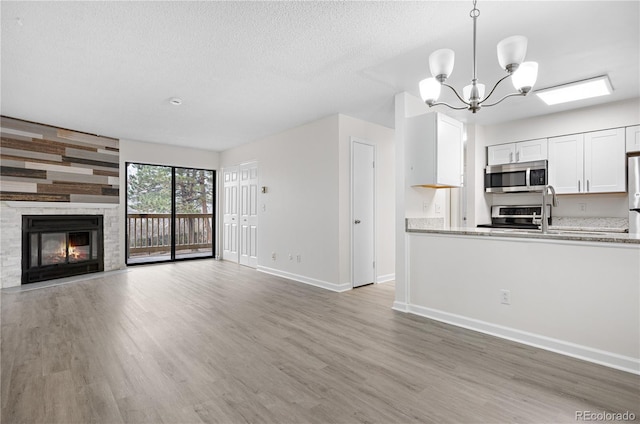 14720 E Kentucky Dr Unit 622, Aurora, CO 80012 - unfurnished living room featuring wood finished floors, baseboards, a chandelier, a fireplace, and a textured ceiling