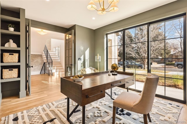 office area featuring light hardwood / wood-style flooring, brick wall, and an inviting chandelier