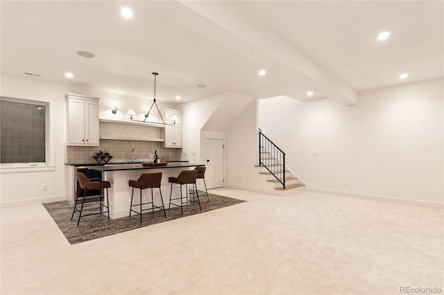 kitchen with white cabinetry, hanging light fixtures, beamed ceiling, carpet floors, and a breakfast bar area