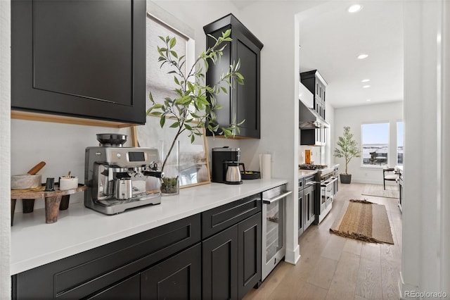 kitchen with wine cooler, high end stainless steel range, and light hardwood / wood-style flooring