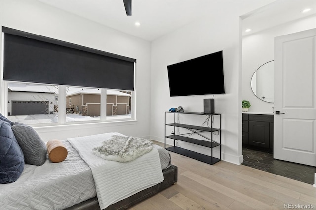 bedroom with ceiling fan, connected bathroom, and light hardwood / wood-style floors