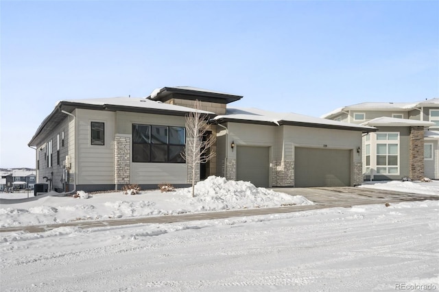 prairie-style home featuring a garage and central AC unit