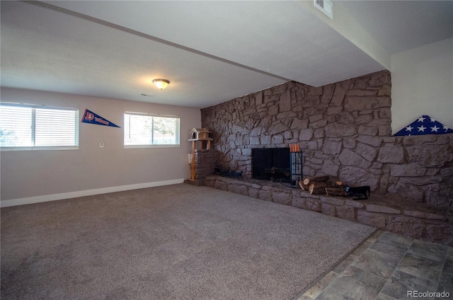 unfurnished living room featuring a stone fireplace and carpet flooring