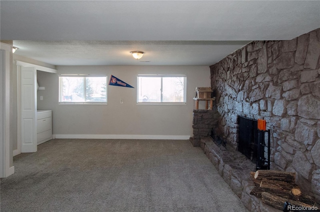 unfurnished living room with a stone fireplace, washer / dryer, carpet, and a textured ceiling