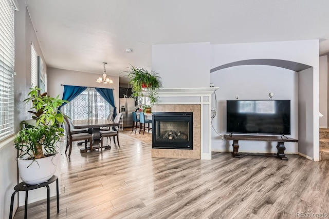 living room featuring a chandelier, hardwood / wood-style flooring, and a tiled fireplace