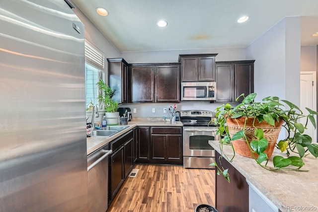 kitchen featuring dark brown cabinetry, sink, stainless steel appliances, and light hardwood / wood-style flooring