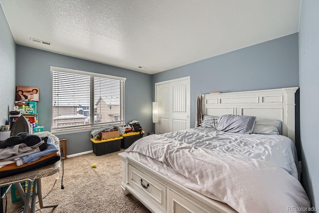 carpeted bedroom featuring a textured ceiling and a closet