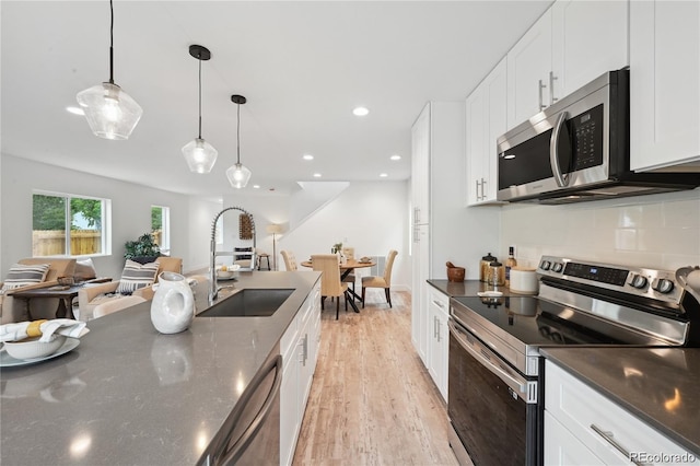 5242 Columbine Ln, Denver, CO 80221 - kitchen featuring appliances with stainless steel finishes, a sink, light wood-type flooring, tasteful backsplash, and white cabinetry