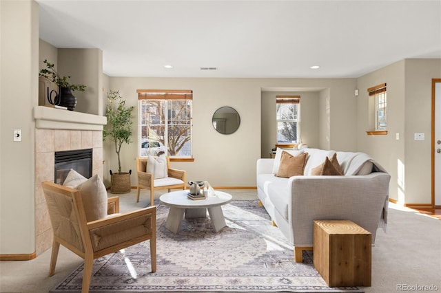 living room featuring light carpet, a wealth of natural light, and a tile fireplace