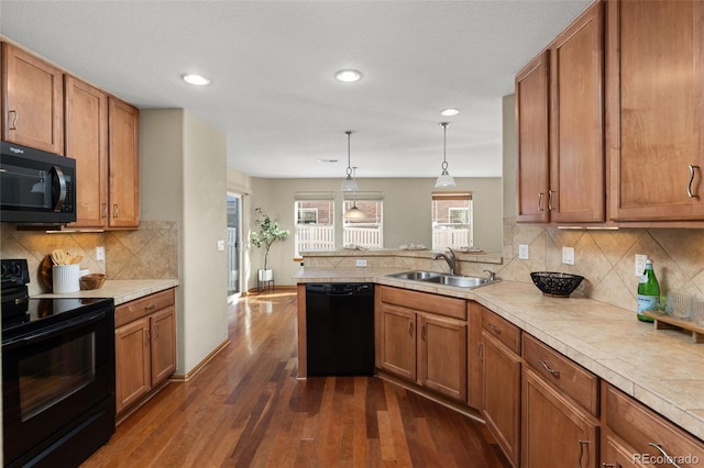 kitchen featuring sink, dark hardwood / wood-style floors, black appliances, decorative light fixtures, and kitchen peninsula