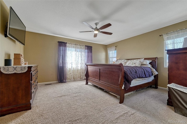 bedroom with a ceiling fan, light colored carpet, a textured ceiling, and baseboards