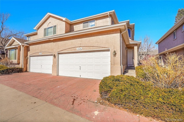 view of front facade featuring an attached garage, decorative driveway, and stucco siding