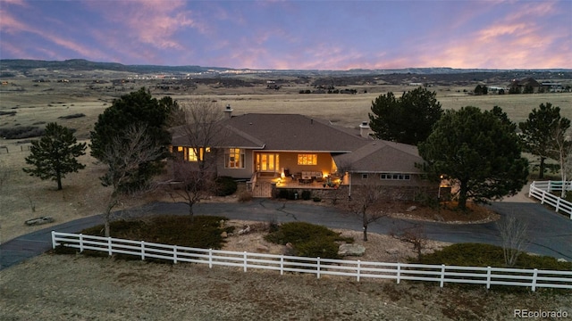 view of front facade with a rural view, a patio, and fence