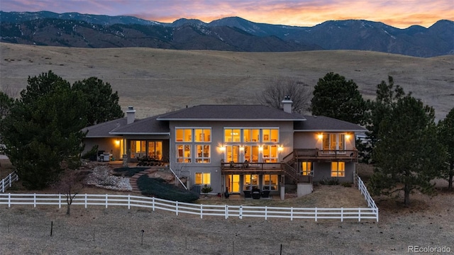 rear view of house featuring stucco siding, stairs, a chimney, fence private yard, and a mountain view