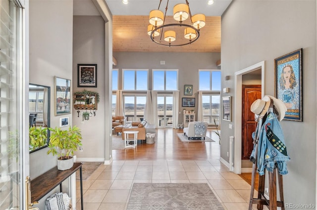 entryway featuring recessed lighting, a high ceiling, light tile patterned flooring, baseboards, and a chandelier