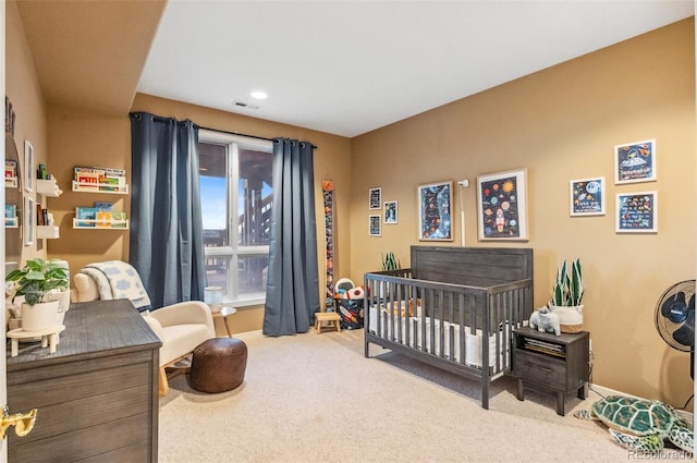 bedroom featuring visible vents, baseboards, carpet, and a crib