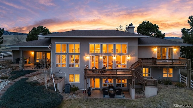 rear view of house featuring stairs, stucco siding, a chimney, and a patio area