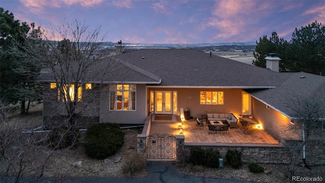 rear view of house featuring stucco siding, french doors, a chimney, a patio, and a gate