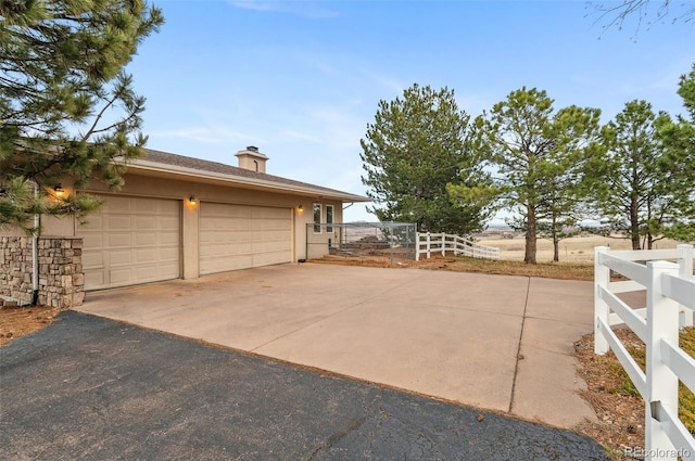 garage featuring fence and driveway