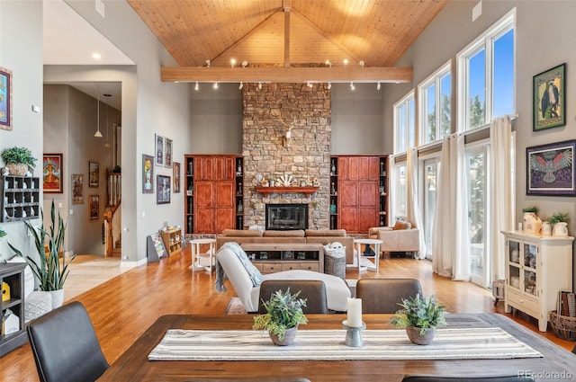 living area featuring high vaulted ceiling, light wood-style floors, a fireplace, baseboards, and wood ceiling