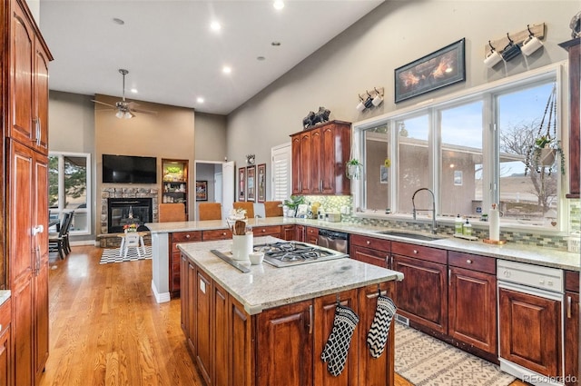 kitchen featuring a sink, a kitchen island, tasteful backsplash, open floor plan, and a stone fireplace