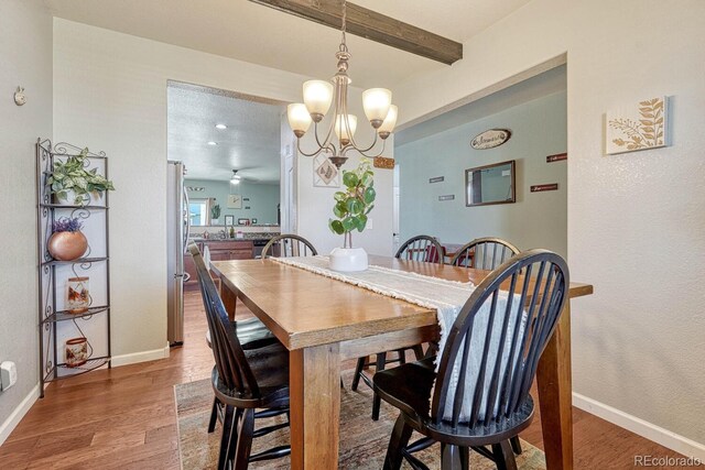 dining space featuring beam ceiling, hardwood / wood-style floors, a textured ceiling, and ceiling fan with notable chandelier