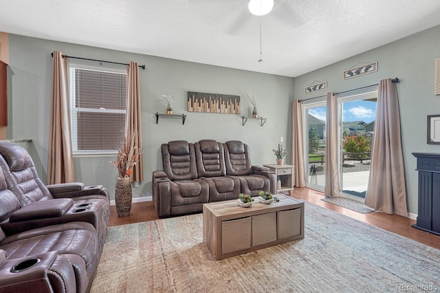 living room featuring ceiling fan, hardwood / wood-style floors, and a textured ceiling