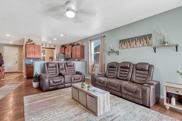 living room with hardwood / wood-style floors, ceiling fan, and a textured ceiling