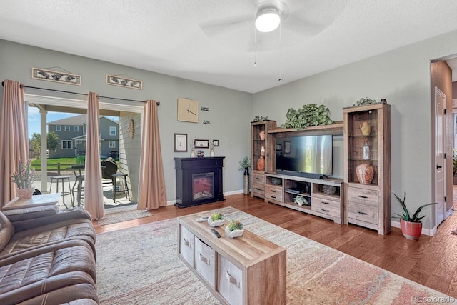 living room with ceiling fan, wood-type flooring, and a textured ceiling