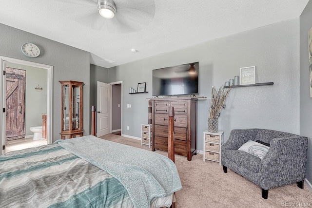 bedroom with light carpet, baseboards, a ceiling fan, ensuite bath, and a textured ceiling