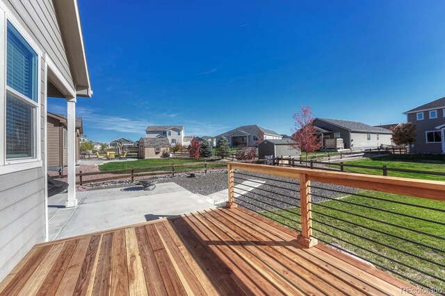 wooden terrace featuring a patio area and a lawn