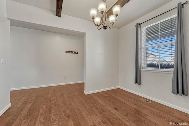 empty room with wood finished floors, visible vents, baseboards, beamed ceiling, and an inviting chandelier