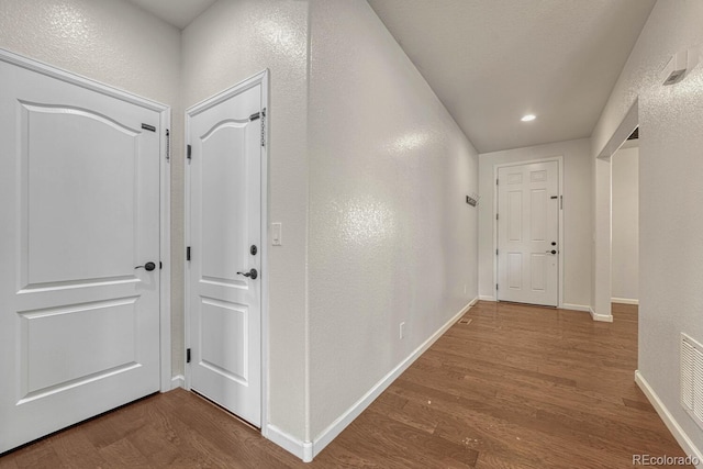 corridor featuring recessed lighting, visible vents, a textured wall, wood finished floors, and baseboards