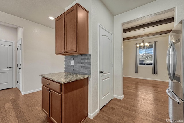 kitchen with decorative backsplash, wood finished floors, freestanding refrigerator, and brown cabinets