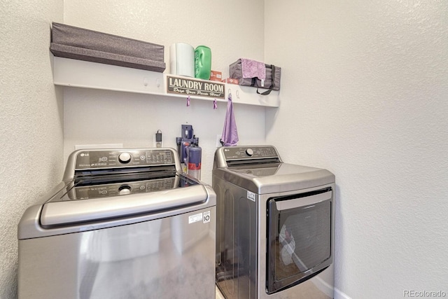 washroom featuring a textured wall, laundry area, and washer and dryer