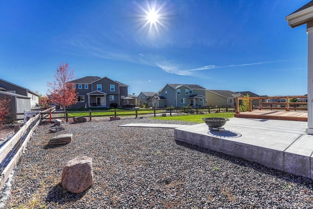 view of yard with a fire pit, a deck, fence, and a residential view