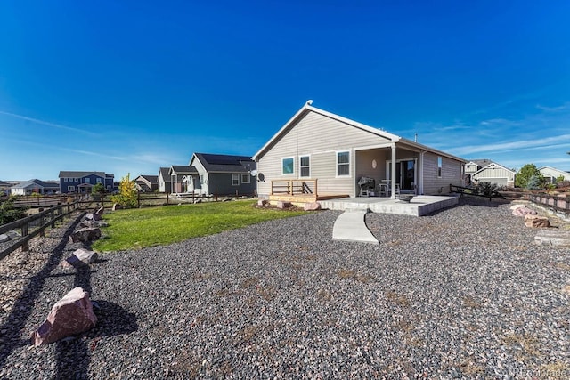 rear view of property featuring a patio area, fence, and a lawn