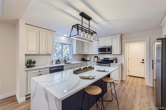 kitchen with sink, a center island, hanging light fixtures, stainless steel appliances, and light stone countertops