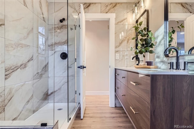 bathroom featuring vanity, an enclosed shower, wood-type flooring, and tile walls