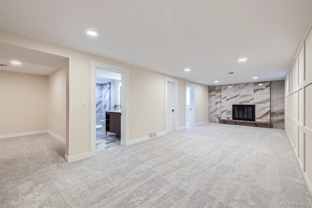 unfurnished living room with light carpet and a premium fireplace