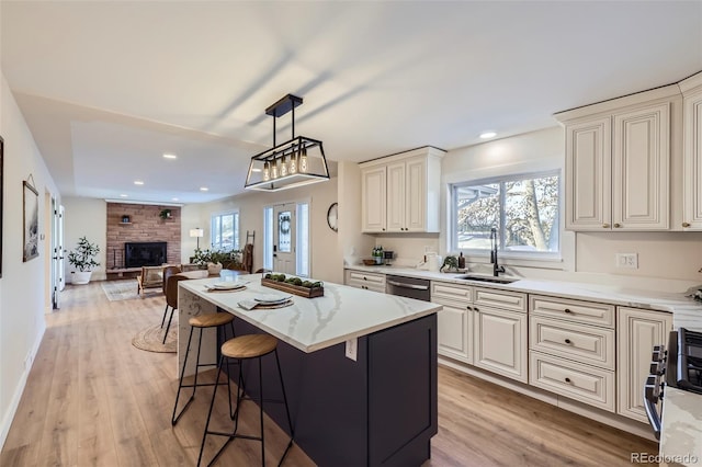 kitchen with a kitchen island, sink, a large fireplace, hanging light fixtures, and stainless steel appliances